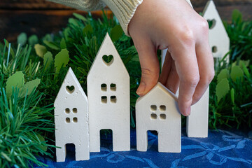 Hand placing white ceramic house into festive village.