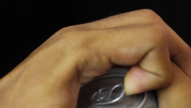 close up of a hand opening a can of drink