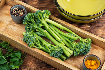Fresh baby broccoli arranged in a wooden tray with spices