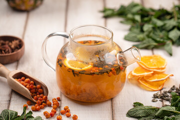 Aromatic sea buckthorn tea brewed with citrus slices herbs and spices served in a glass teapot on...