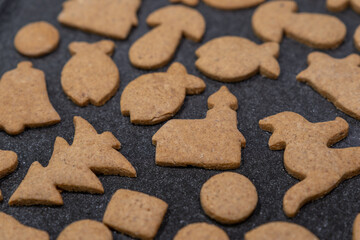 Baked gingerbread cookies lying on a baking tray with various shapes.
