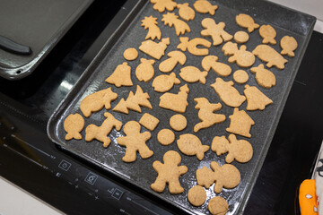 Baking tray with baked gingerbread cookies of various shapes.
