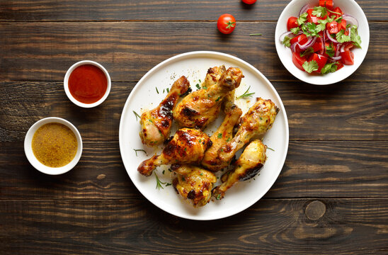 Barbecue roasted chicken drumsticks served with sauce and vegetable salad