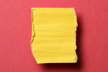One single yellow torn ripped wrinkled crumpled blank paper note with drop shadow, folded edge and copy space for text on red background