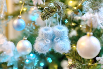 Knitted blue booties hanging on a Christmas tree. The concept of wishing for a child in the new year, making a wish at Christmas, New Year. 