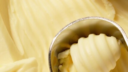 Butter is scraped off with a special butter knife from a pack of butter into a recognizable round shape. Extreme macro close-up, perfect for culinary and advertising projects.