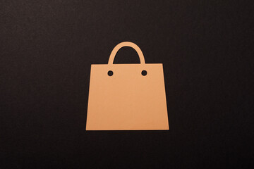 A cut-out paper shopping bag on a black backdrop. Perfect for representing online shopping, retail, and sales