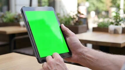 Person Using Tablet with Green Screen in Indoor Setting.