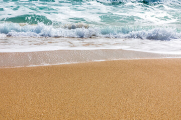 Sunny beach with gentle waves lapping white sand shoreline under a clear sky
