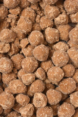 A vertical close-up shot of a dense, textured background composed entirely of small, round, brown coated tapioca pearls