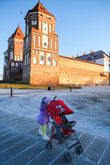 Belarus, Misk, 03.01.2024 Little girl pushing an empty stroller on a frosty winter day in front of...
