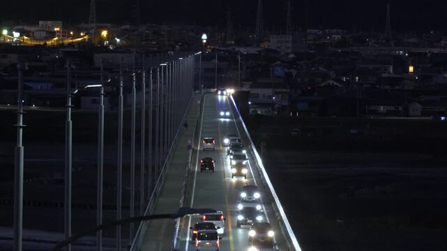 河川にかかる橋の上を車が走る夕方から夜の風景

