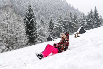 Child sledding downhill on snowy hillside during calm winter outdoor activity