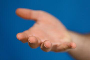 Obraz premium Close up shot of hand reaching forward, offering help or assistance, isolated against a vibrant blue backdrop.