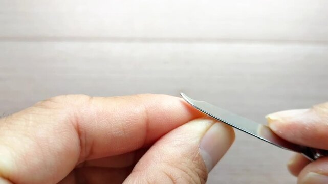 Health concept. Close-up image of sharpening or trimming a thumb. Nail cutting concept. Unhealthy lifestyle: long and dirty nails. Body hygiene concept. Soft focus, selective focus.