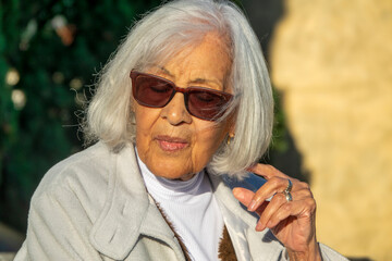 Elegant Senior Woman with White Hair Wearing Sunglasses Outdoors