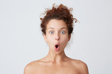 Close up shot of amazed cute curly young woman with perfect healthy skin looks shocked and surprised isolated over white background Feels excited after shower