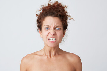 Cropped shot of mad furious young woman with curly hair and perfect skin looks angry an aggressive isolated over white background Feels angry and looks crazy