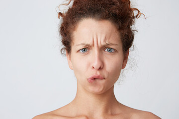 Cropped shot of worried thoughtful young woman with curly hair and healthy fresh skin looks stressed and biting her lip isolated over white background Standing half naked after shower