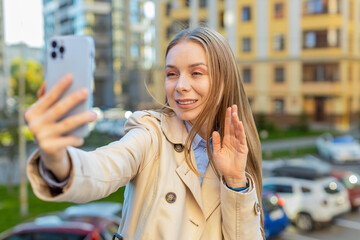 Mature businesswoman blogger taking selfie on smartphone, communicating video call online with subscribers recording stories for social media vlog outdoors. Girl standing on urban downtown street.