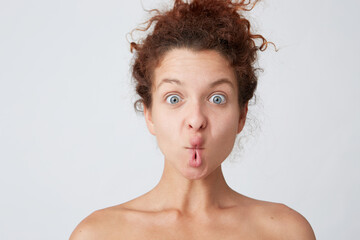 Cropped shot of funny cute young woman with curly hair and healthy skin making fish face with lips and having fun isolated over white wall Comical expression