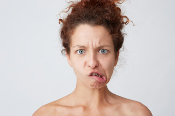 Cropped shot of angry crazy young woman with curly hair and perfect skin after applying mask or cream making irritated funny face and joking isolated over white background Amusing and comical girl
