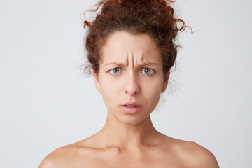 Horizontal shot of sad worried young woman with perfect skin after applying mask or cream after shower feels stressed and have problems isolated over white background