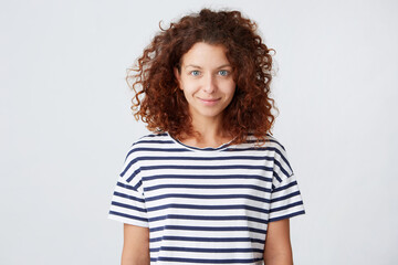 Portrait of happy beautiful young woman with long curly hair wears striped t shirt looks confident and smiling isolated over white background