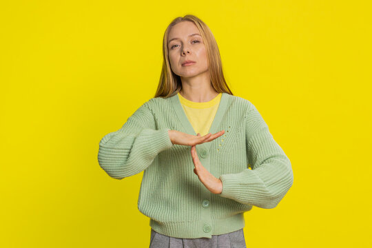 Tired serious upset Caucasian middle-aged woman showing time out gesture, limit or stop sign, no pressure, I need more time, take a break, relax, rest, help. Adult girl isolated on yellow background