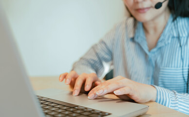 Woman with headset working at computer in call center office for CRM, customer service, and sales support. Advisor using mic for telemarketing, legal assistance, or technical support communication.
