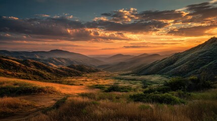 Fototapeta premium Sunset casts light over rolling hills and valleys in a landscape scene with clouds in the sky and the sun setting in the background during evening hours