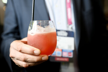 Person holding pink cocktail in glass at professional event