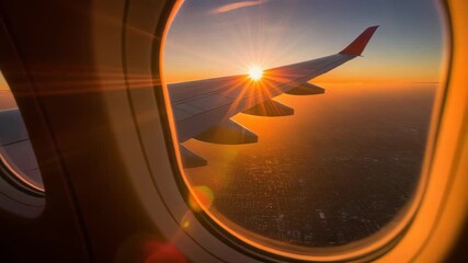 View from airplane window showing wing and bright sun flare over city landscape at sunset, concept for travel advertisement, global business logistics and holiday destination marketing
