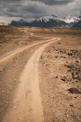 Empty winding road snaking through a remote and rugged wilderness. A powerful image of isolation and the vastness of the natural world, far from civilization