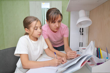 Mother helping daughter to complete school tasks.