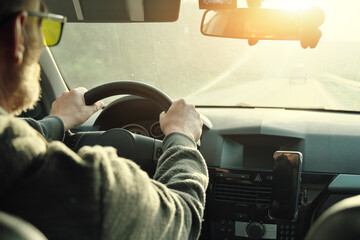 Men&rsquo;s driver's hand holding steering wheel of car while driving.