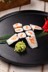 Classic salmon maki sushi rolls served with wasabi and pickled ginger on a black plate © Hihitetlin