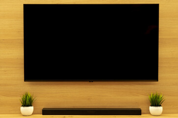 Modern minimalist living room interior design: 55-inch LED Smart TV mockup with soundbar, black blank screen template, and artificial greenery on a stylish oak wall