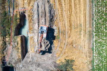 Excavator digging trench in farm field The Concept of Construction