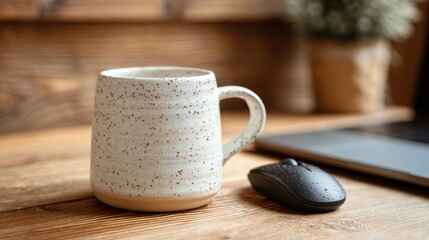 Coffee mug and computer mouse on wooden table in workspace during day