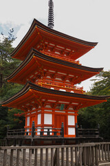 Obraz premium Kyoto.Three-Tier Japanese Pagoda Temple in Autumn Garden Setting with Red Wood and Stone Fence