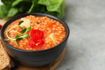 Delicious lentil soup with vegetables served on grey table, closeup. Space for text