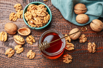Honey in jar, dipper and walnuts on wooden table, flat lay