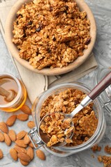 Tasty granola in glass jar and ingredients on light grey table, flat lay