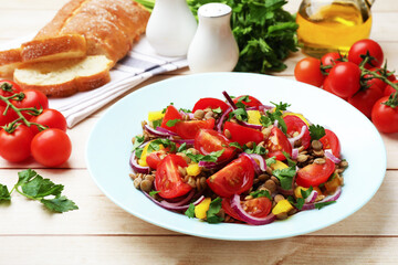 Delicious lentil salad and ingredients on light wooden table, closeup