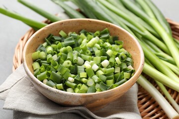 Whole and cut fresh green onions on grey table, closeup