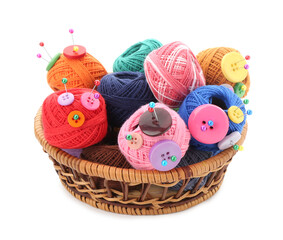 Many bright yarns with pins and buttons in wicker basket isolated on white
