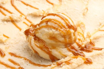 Tasty ice cream with caramel sauce as background, closeup