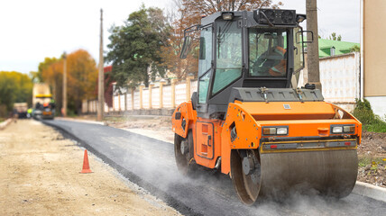 Road roller lays fresh asphalt during city street repairs
