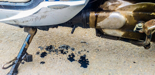Motorbike Engine oil leaking on road asphalt, extra oil leak tube, mechanical emergency at garage...